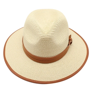 Détail d'un chapeau fedora en paille beige clair avec ruban en cuir marron et bord gansé