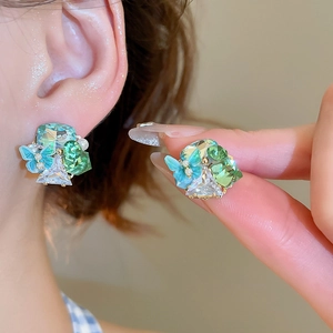 Detail view of 18k gold-plated butterfly stud earrings with green crystals and pearls