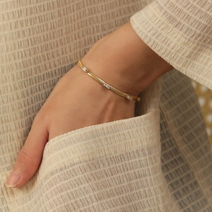 Elegant gold snake chain bracelet with rectangular zircons on model's hand
