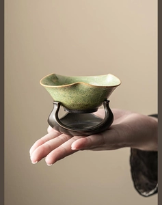 Macro shot of green kiln-glazed ceramic tea strainer with elegant wavy edges and base