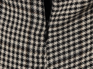 Macro detail of the invisible black zipper and houndstooth fabric texture on this dress