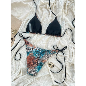 Flat lay of leopard print bikini with halter top and side-tie bottoms on textured white leaf