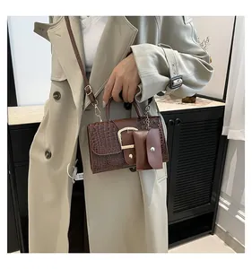Détail du sac à motif crocodile marron foncé avec boucle fer à cheval dorée et pochette