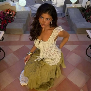 Detail of white lace off-shoulder top with ribbons paired with olive green skirt