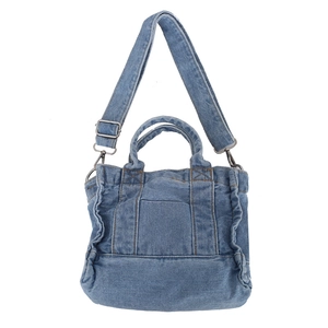 Detailed texture of blue denim tote bag showing stitching and silver metal hardware accents