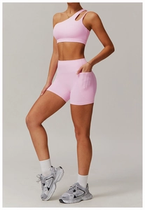 Side view of pink one-shoulder sports bra and high-waisted shorts with side pocket