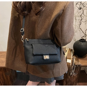 Detail of black pleated PU leather crossbody bag with golden twist lock and adjustable strap