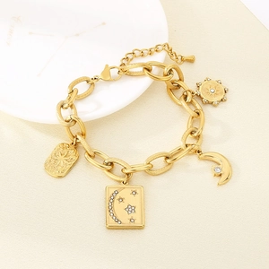 Detail of gold chunky link bracelet with moon and rhinestone star charms on white plate