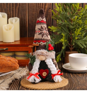 Detail of Christmas gnome with knitted snowflake hat, plush braids and red heart decor