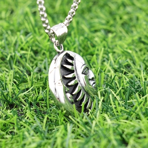 Punk style stainless steel sun and moon pendant on green grass at a 45-degree angle