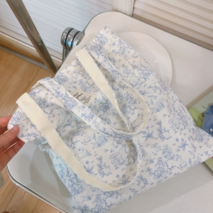 Detailaufnahme des hellblauen Hasen- und Blumenmusters auf der weißen Baumwolltasche