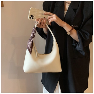 Detail of off-white hobo bag with stylish geometric silk scarf on the handle