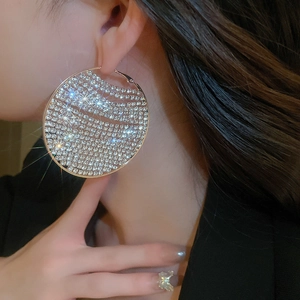 Macro shot of oversized geometric round hoop earrings encrusted with sparkling rhinestones
