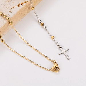 Two-tone stainless steel ball chain necklace with cross pendant on stone display
