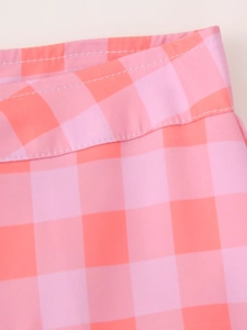 Detailed close-up of the pink and orange plaid fabric and stitching on casual trousers
