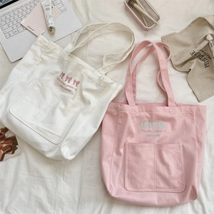 Detailed embroidery and large front pocket on canvas tote bag in lifestyle setting