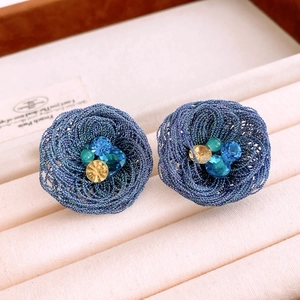 Macro detail of blue woven floral earring featuring sparkling blue and yellow crystals