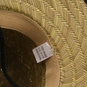 Detailed close-up showing 100% natural grass woven texture and black inner lining of the hat