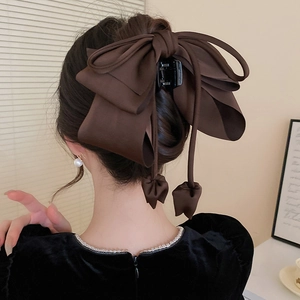 Détail d'une grande pince à cheveux avec nœud en satin marron foncé sur un mannequin