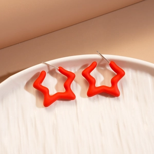 Macro detail of red matte star-shaped resin earrings on white ceramic tray