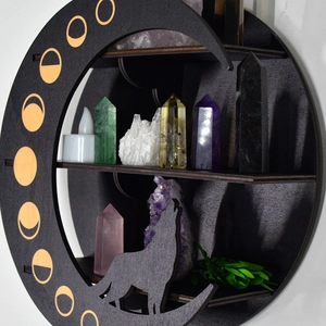 Detail of round black wooden shelf featuring lunar phases and wolf silhouette design