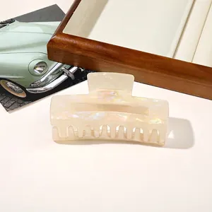 Detail view of large iridescent cream hair claw clip for elegant updo hairstyles