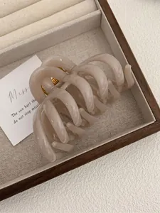 Macro shot of octopus-shaped hair claw clip in nude beige resin with gold spring detail