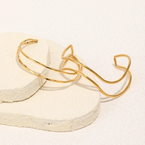 Minimalist 18K gold plated wavy double line open bangle on a textured stone display