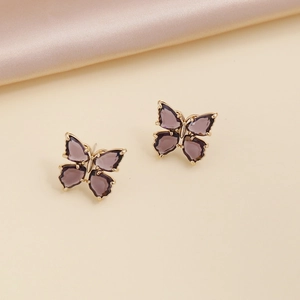 Macro shot of butterfly earrings featuring purple crystals and gold-tone metal borders
