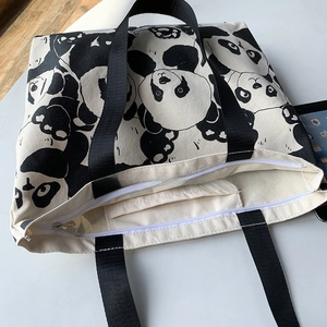 Detail of canvas tote bag with zipper closure and internal pocket showing panda print