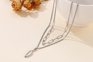 Detail of silver double-layered necklace featuring feather pendant and paperclip chain