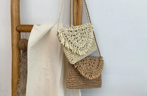 Detail of handmade straw shoulder bags with tassels hanging on a wooden ladder