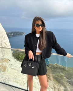 Detail shot of a black oversized jacket with ribbed cuffs and a metallic eyelet mini skirt