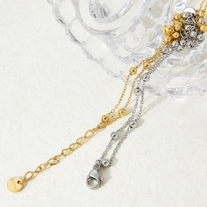 Double-layered stainless steel anklet with gold and silver beads on a textured background