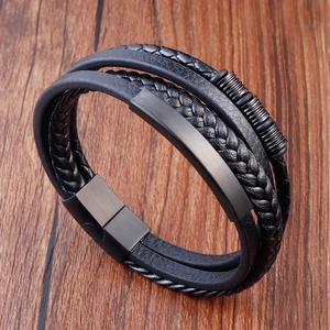 Multi-layer woven black leather bracelet for men with magnetic metal clasp on wooden desk
