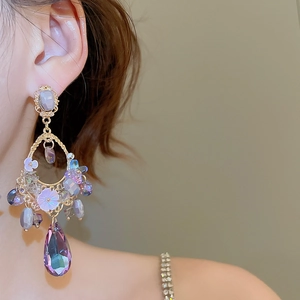 Detail of vintage style drop earrings with purple crystals and water drop pendant on model