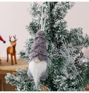 Christmas gnome plush hanging on a snowy pine branch with festive holiday ornaments