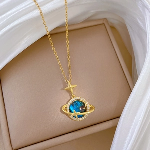Dettaglio di una collana con ciondolo a pianeta dorato con pietra galassia blu e zirconi