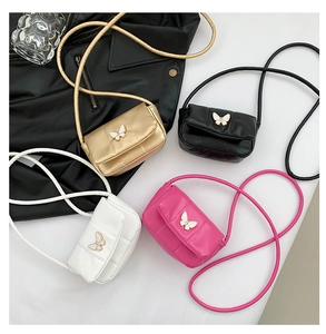 Détail de mini sacs à bandoulière avec fermoir papillon en or, noir, blanc et rose fuchsia