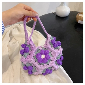 Detail of handmade crochet purple flower bag with elegant pearl button and knit texture