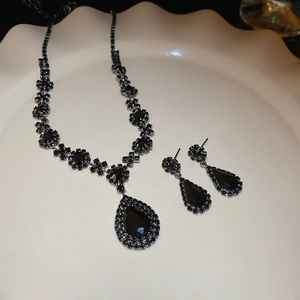 Detailed view of luxury black gemstone necklace and earrings set on ceramic plate