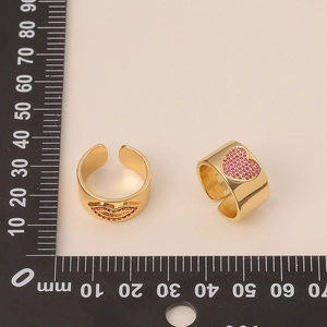 Macro detail of gold 18K plated open rings featuring red lip and heart pave designs