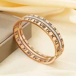 Detailed shot of rose gold Roman numeral bangles with crystals on silk background