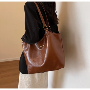 Detail of soft brown faux leather tote bag with metallic hardware and slim shoulder straps