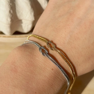 Minimalist knot design gold and silver titanium steel bracelets shown on a wrist