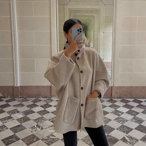 Oatmeal wool cape coat featuring knit patchwork sleeves and deep front pockets