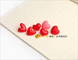 Close-up of heart-shaped brooches in red and pink finishes with a gold butterfly clutch
