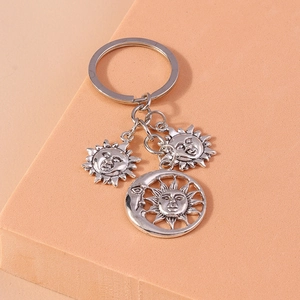 Detailed view of silver sun and moon keychain pendants on a geometric background