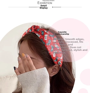 Detail of red Christmas knotted headband with festive prints on warm indoor model