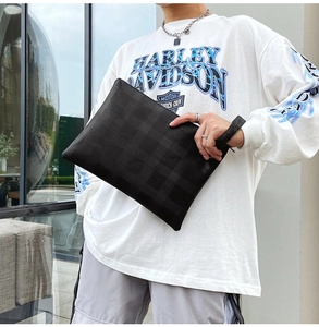 Dettaglio della texture goffrata a scacchi neri sulla borsa a mano da uomo